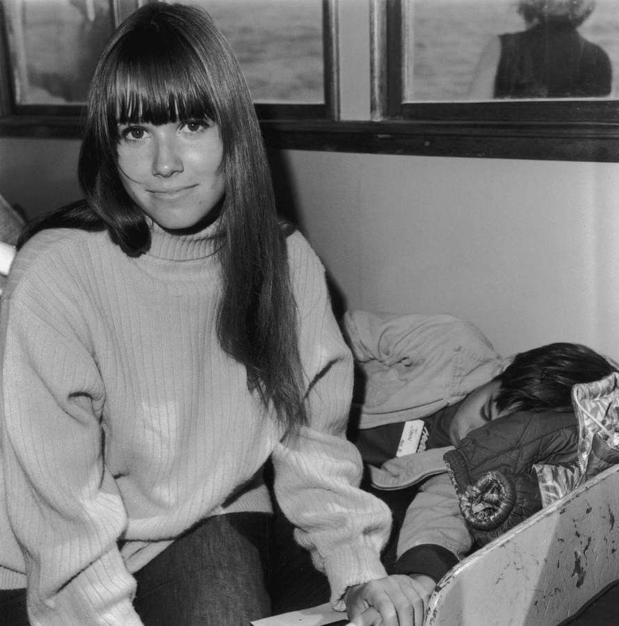 Frau im Rollkragenpullover lächelt neben schlafendem Kind im Boot. — Barbara Hershey Bilder