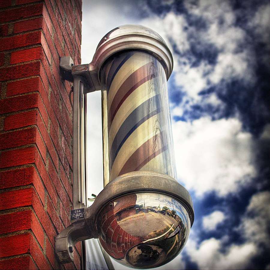 Barber pole mounted on brick wall reflecting street and sky — Barber Pole Wallpaper