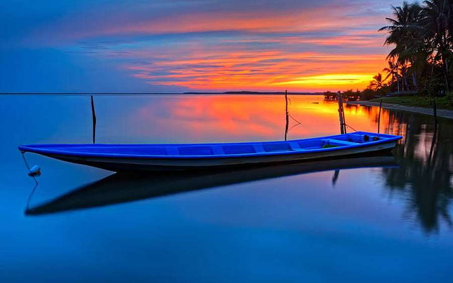 Barco azul en aguas tranquilas al atardecer con palmeras y reflejo colorido del cielo. — Barco Fondos de pantalla