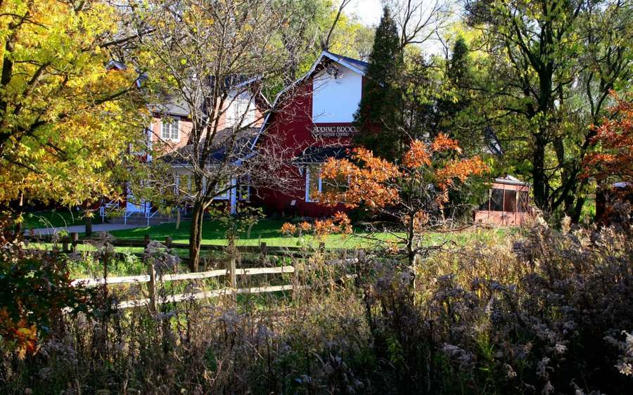Red barn and white house surrounded by autumn trees and wooden fence. — Barn Background