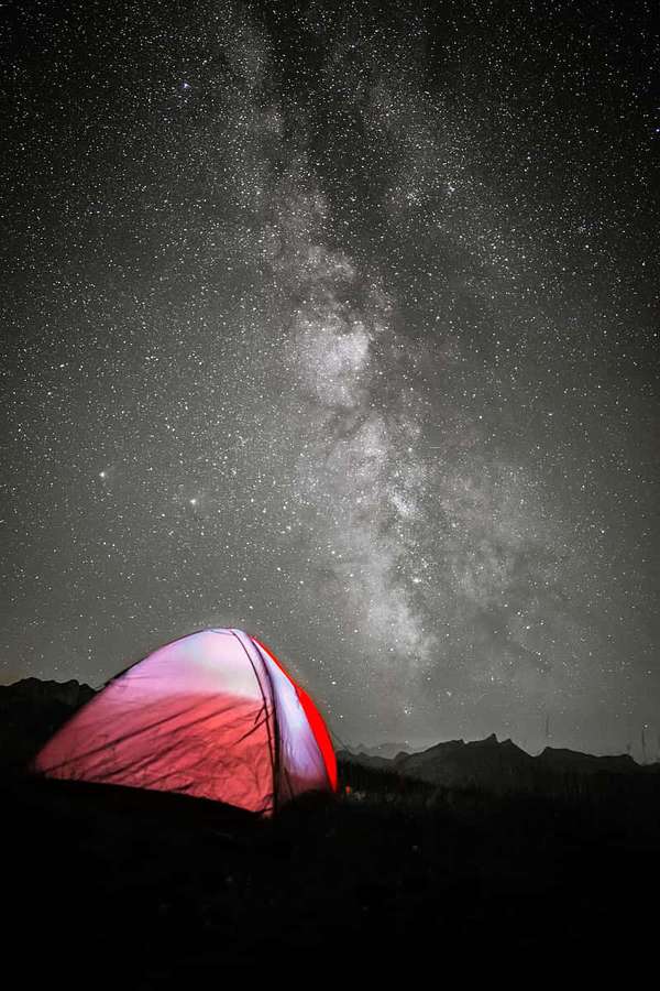 Uma tenda vermelha iluminada sob um céu noturno estrelado com a Via Láctea visível. — Barraca Papéis de Parede