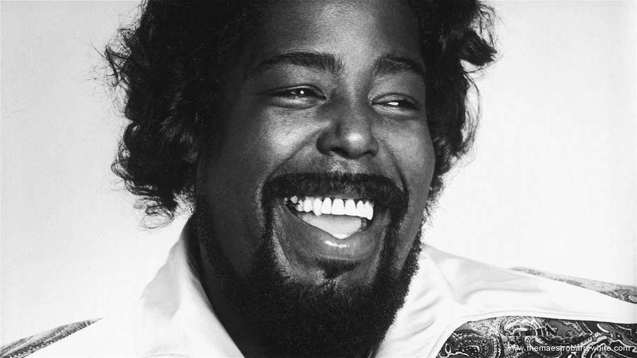 A man with a joyful laugh and curly hair in a black and white studio portrait. — Barry White Wallpaper