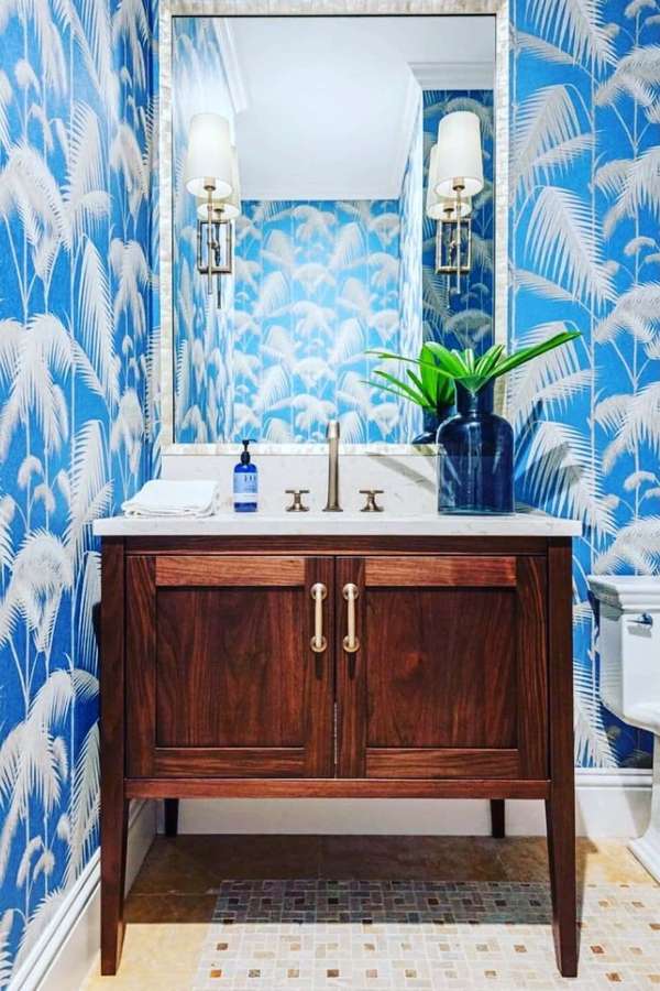 Blue palm leaf wallpapered bathroom with wooden vanity and gold fixtures. — Bathroom Wallpaper