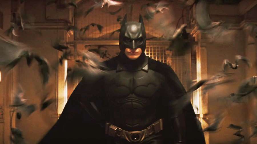Batman surrounded by flying bats in a dark urban setting. — Batman Begins Wallpaper