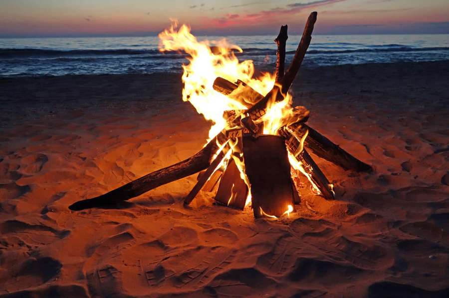 Campfire on beach at sunset with ocean waves — Beach Bonfire Wallpaper