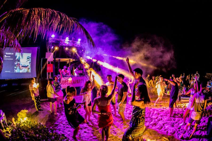 Night beach party with dancing people under purple lights and smoke. — Beach Dance Party Wallpaper