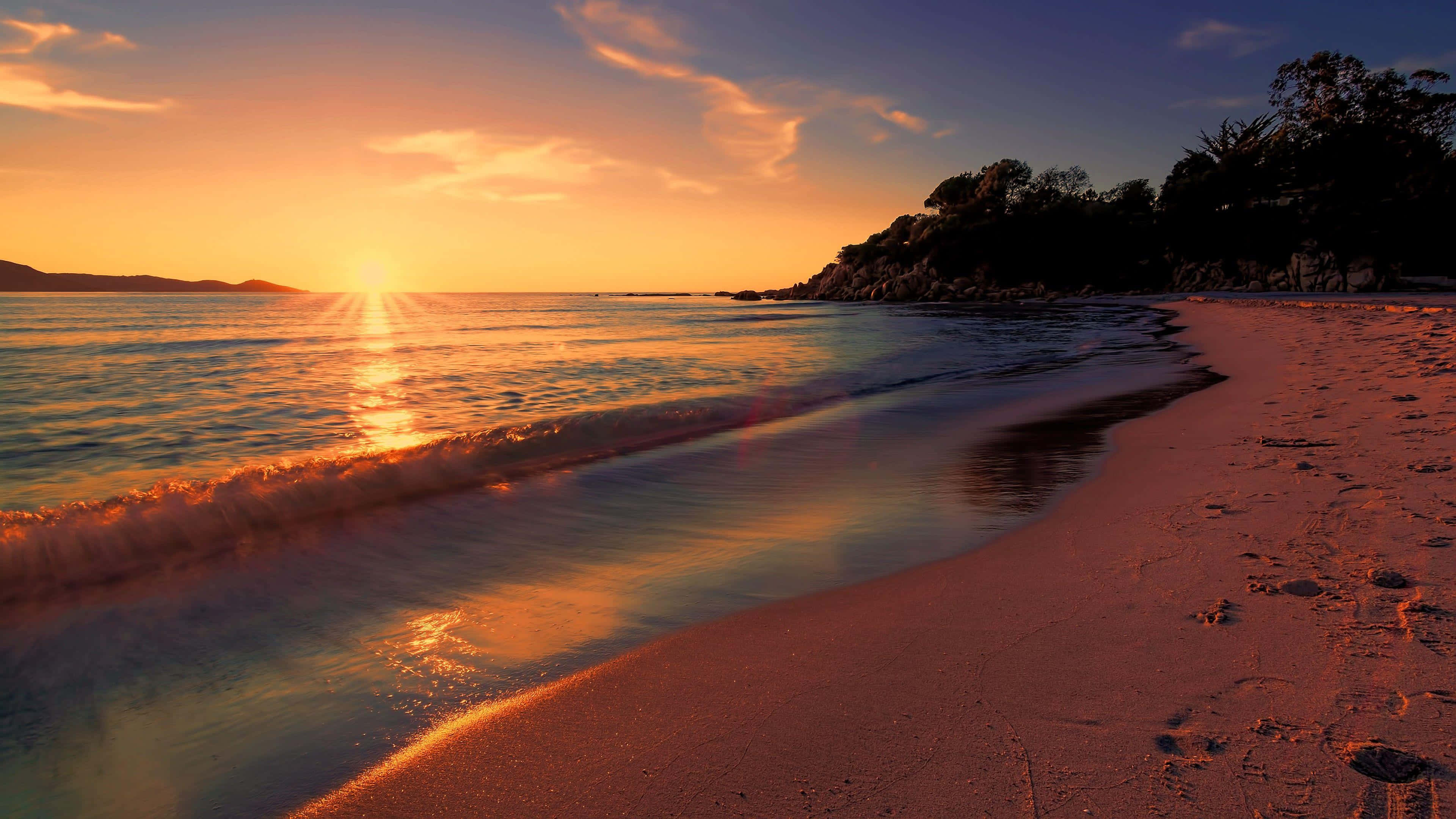 Sunset over ocean with waves washing onto sandy beach — Beach Sunset Wallpaper