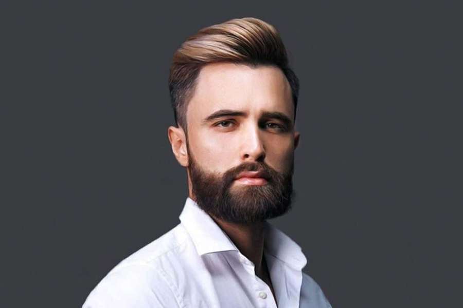 A man with a beard and styled hair in a white shirt against a gray background. — Beard Picture