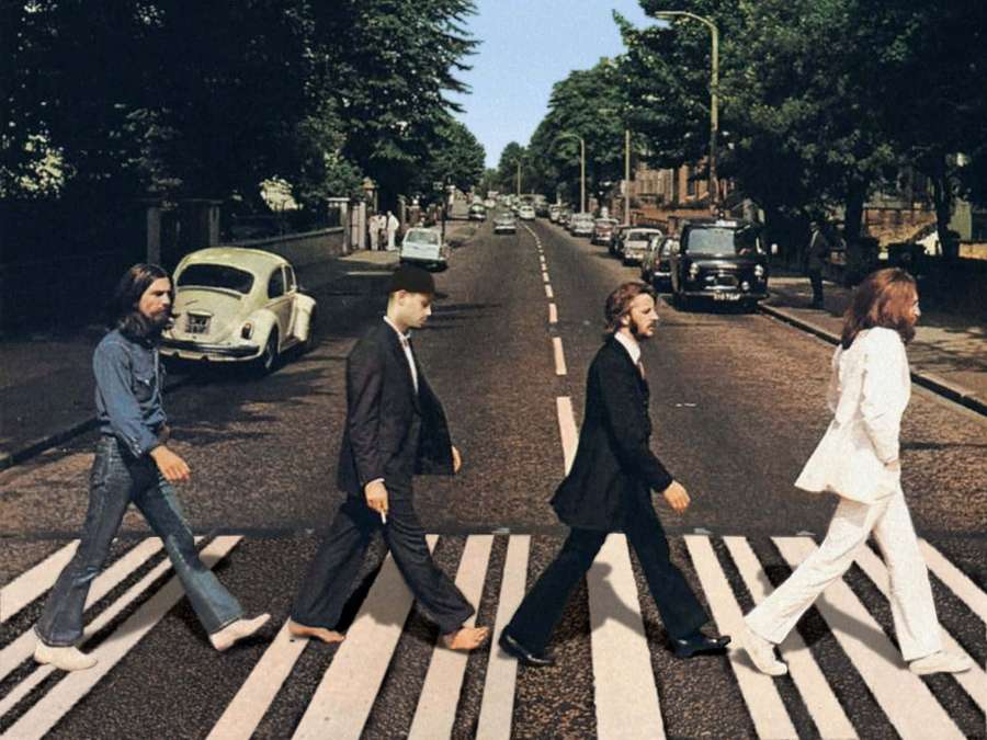 Four men crossing a street zebra crossing in 1960s attire — Beatles Background