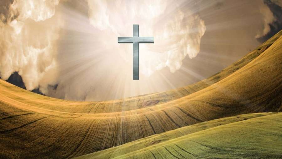 A glowing cross shines above golden rolling hills under a dramatic sky. — Beautiful Cross Wallpaper