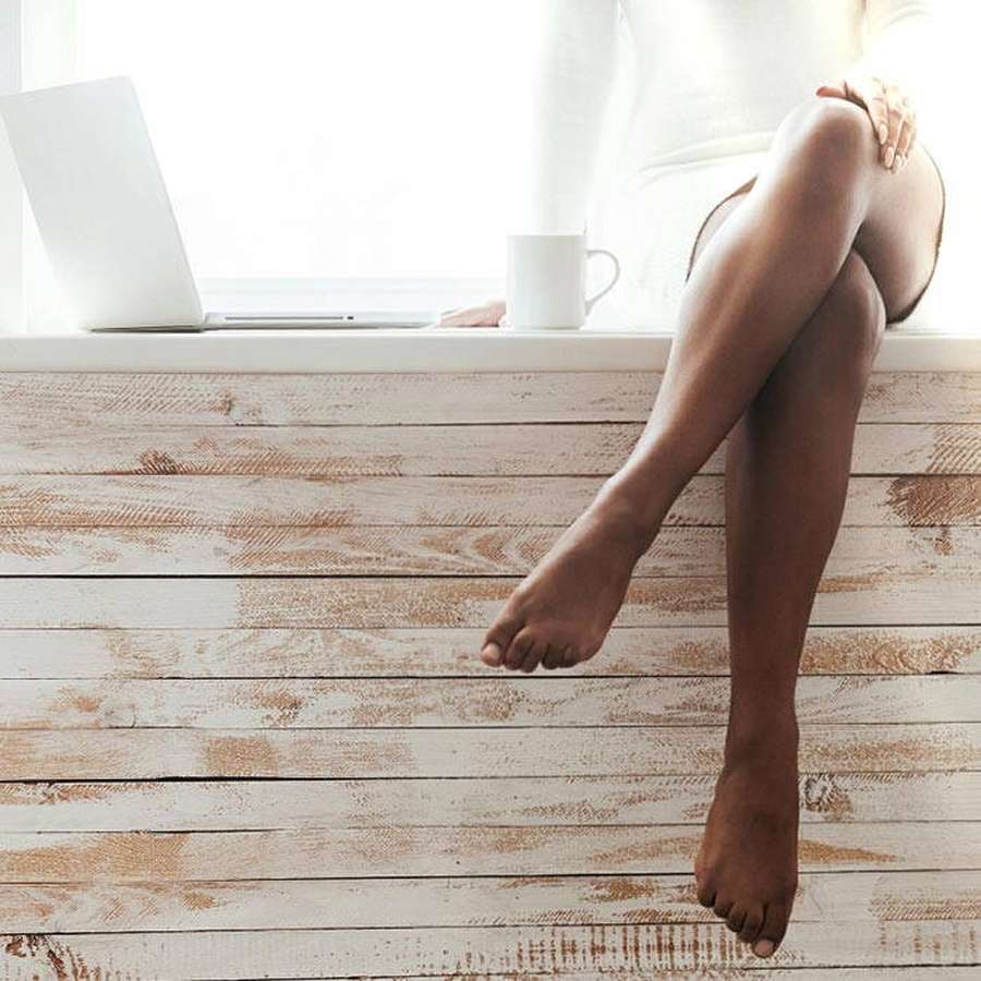 Person sitting barefoot on windowsill with laptop and mug in bright light — Beautiful Legs Wallpaper