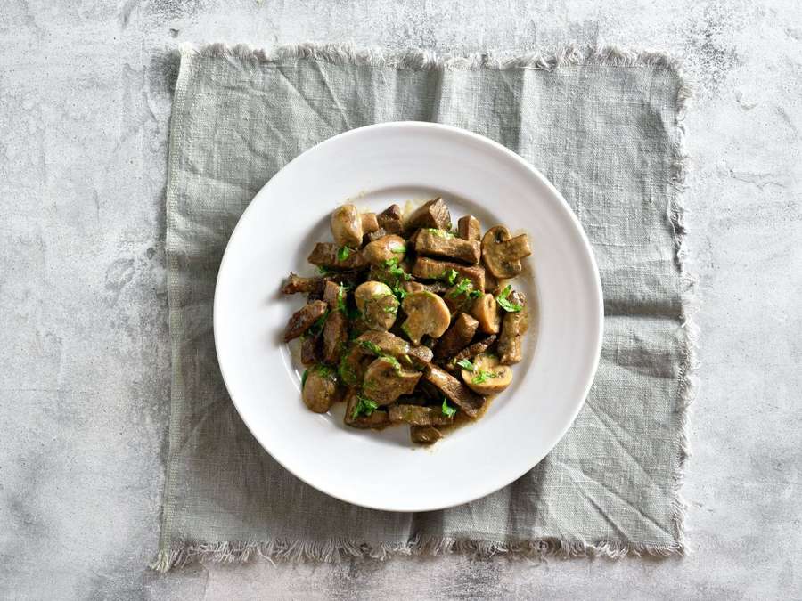 Sautierte Pilze und Fleisch mit Petersilie auf einem weißen Teller über Leinen. — Beef Stroganoff Bilder