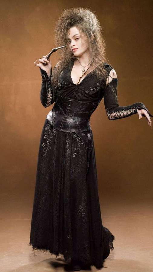 A woman in a black gothic lace gown holding a curved blade in a studio. — Bellatrix Background