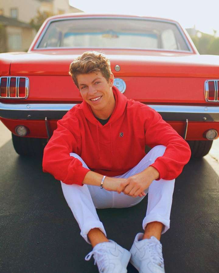 Young man in red hoodie sitting in front of red classic car — Ben Azelart Wallpaper