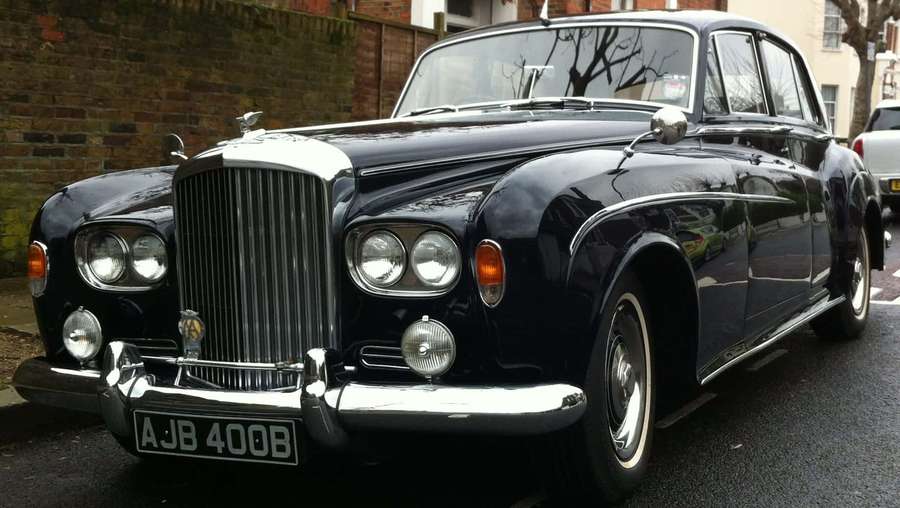 Classic black Bentley with chrome grille parked on wet city street. — Bentley S3 Wallpaper