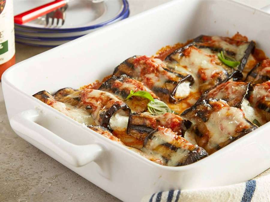 Parmesana de berenjena horneada con queso derretido y albahaca fresca en una fuente blanca. — Berenjena Fondos de pantalla