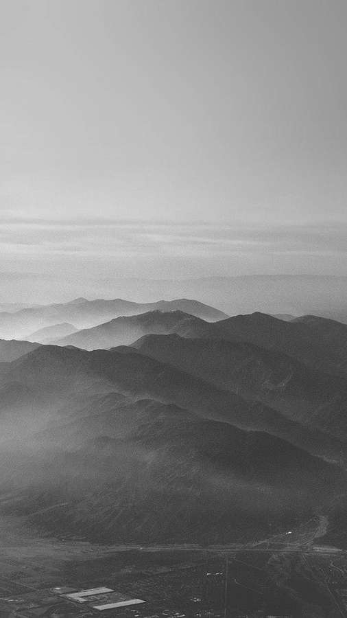 Luftaufnahme von geschichteten Bergketten, die in atmosphärischem Dunst in Schwarz-Weiß verblassen. — Berg iPhone Wallpaper