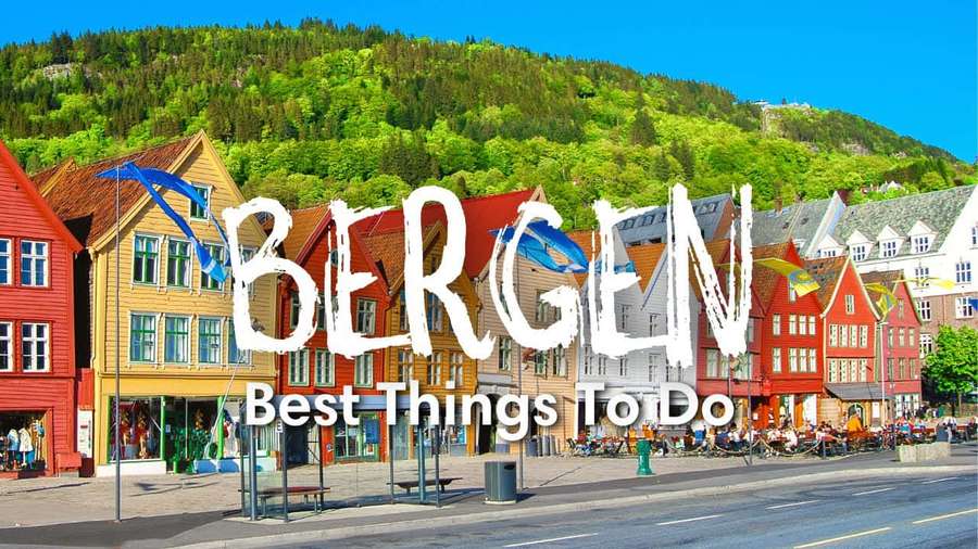 Colorful wooden houses along a sunny waterfront street in Bergen Norway with green hills behind. — Bergen Wallpaper