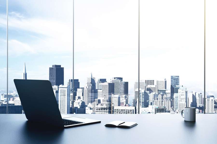 Laptop notebook and mug on desk with city view through large windows — Best Office Background