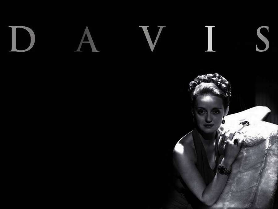 Eine Frau in einer Pelzstola posiert unter dramatischer Beleuchtung mit 'DAVIS'-Text darüber. — Bette Davis Wallpaper