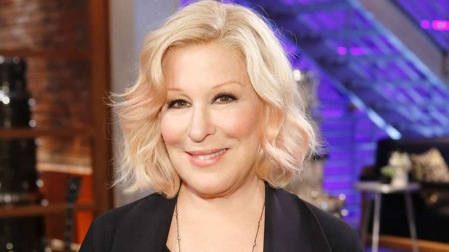 Tom DeLonge sorrindo em um estúdio com iluminação roxa e paredes de tijolos. — Bette midler Papéis de Parede