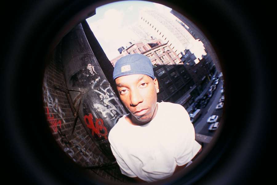 Young man in blue cap looking through fisheye lens at graffiti alley — Big l Wallpaper