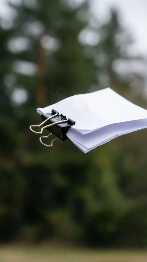 A binder clip with paper flying in the wind, dynamic motion. — Binder Clip Picture