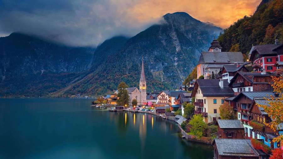 Ein charmantes Dorf an einem ruhigen See mit Bergen im Hintergrund in der Dämmerung. — Bing Hintergrundbild