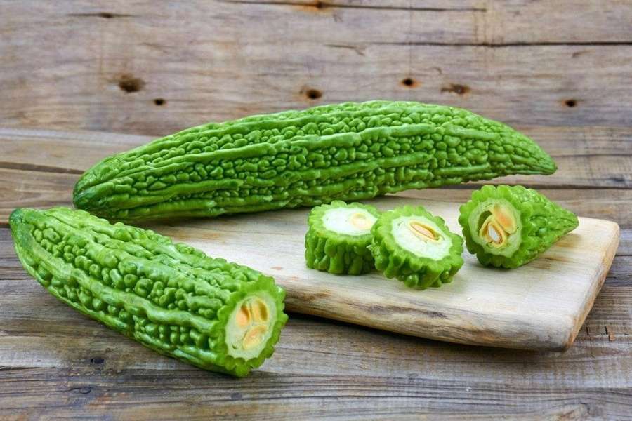 Fresh green bitter melon sliced open on a wooden cutting board. — Bitter Gourd Wallpaper