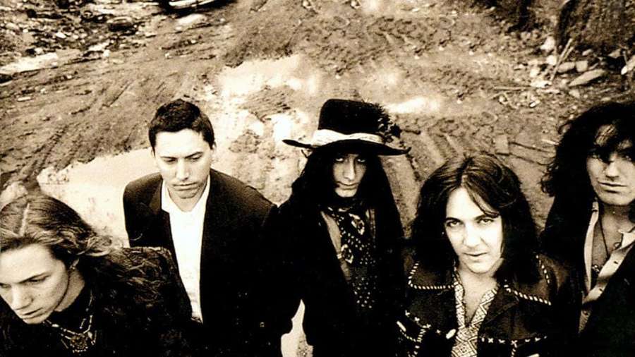 Five men in dark clothing and hats standing on a dirt path with serious expressions. — Black Crowes Wallpaper