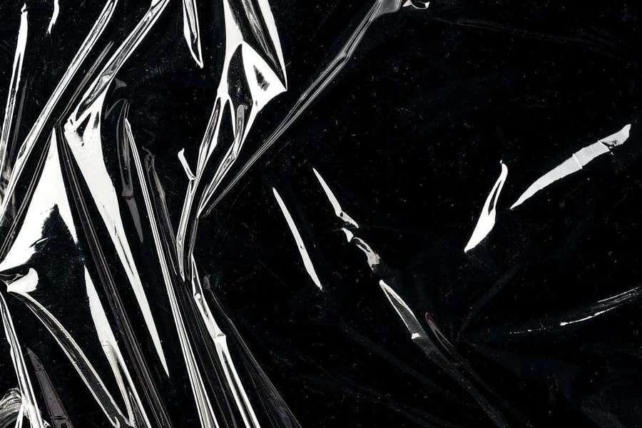 Crinkled black plastic film with shiny silver highlights. — Black Plastic Background