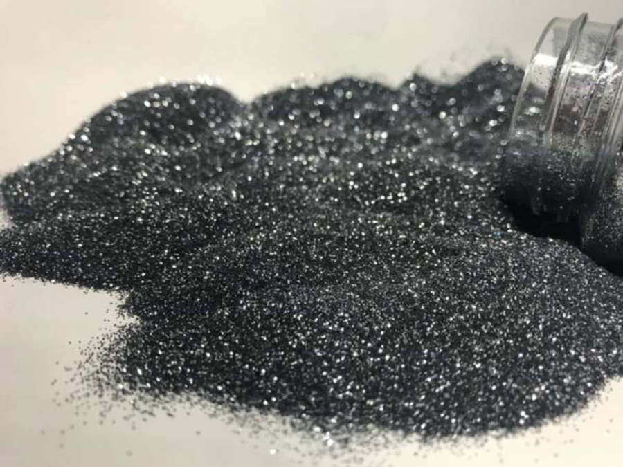 Black glitter spilled from a jar on a white surface — Black Powder Wallpaper