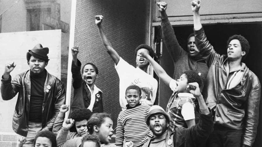 Group of people protesting with raised fists on a building balcony. — Black Power Wallpaper