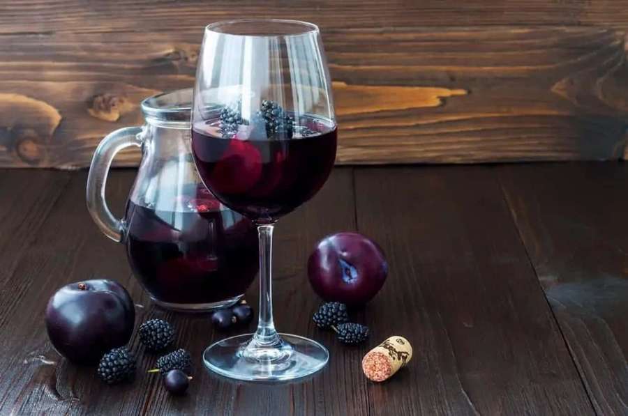 A glass and pitcher of red wine with fruit on a wooden table. — Blackberry Wine Wallpaper
