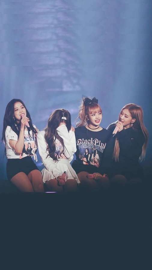 Four female K-pop idols sitting on stage holding microphones under blue lights. — Blackpink Cute Wallpaper