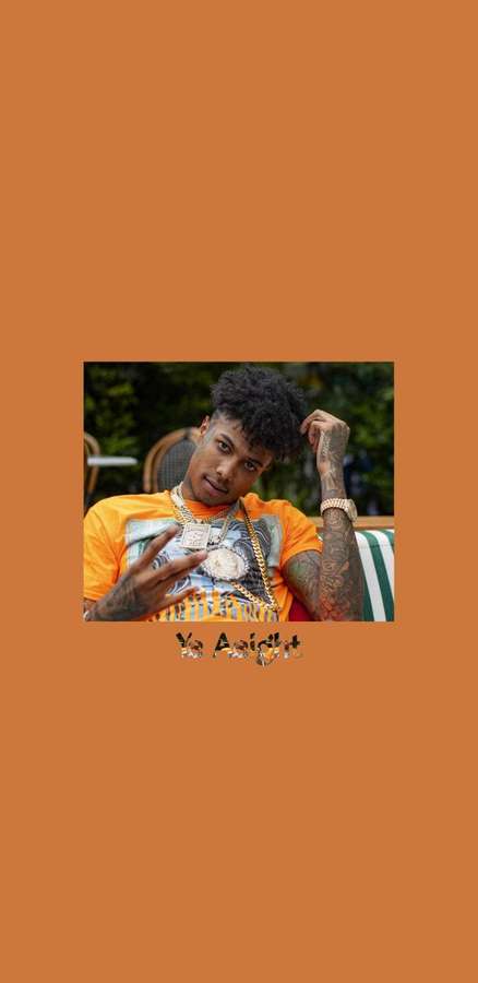 Junger Mann mit Tattoos und Goldschmuck posiert draußen in orangefarbenem Hemd. — Blaues Gesicht Wallpaper