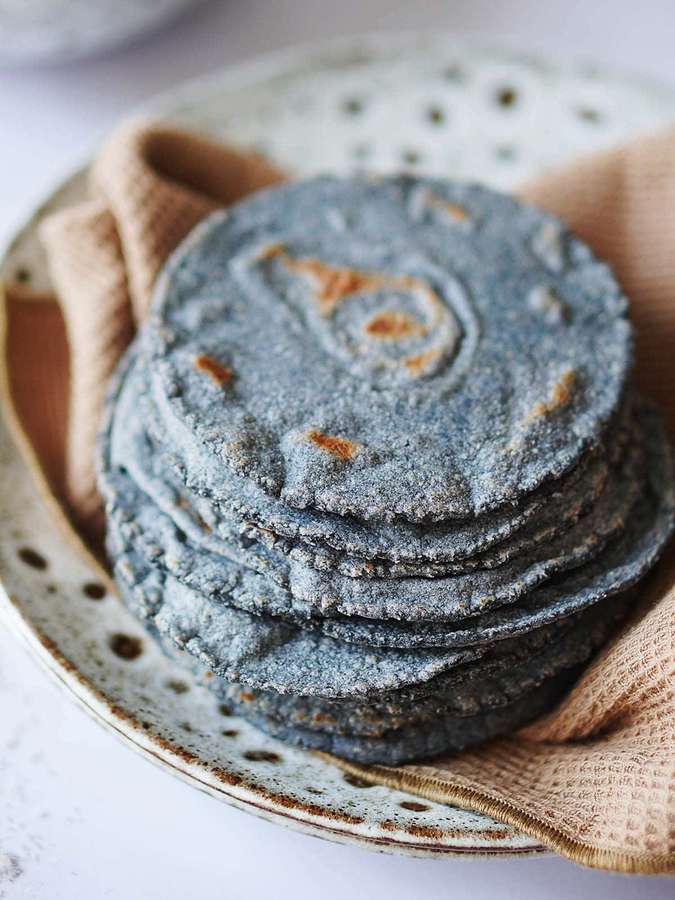 Stack of blue corn tortillas on a ceramic plate with beige cloth. — Blue Chips Wallpaper