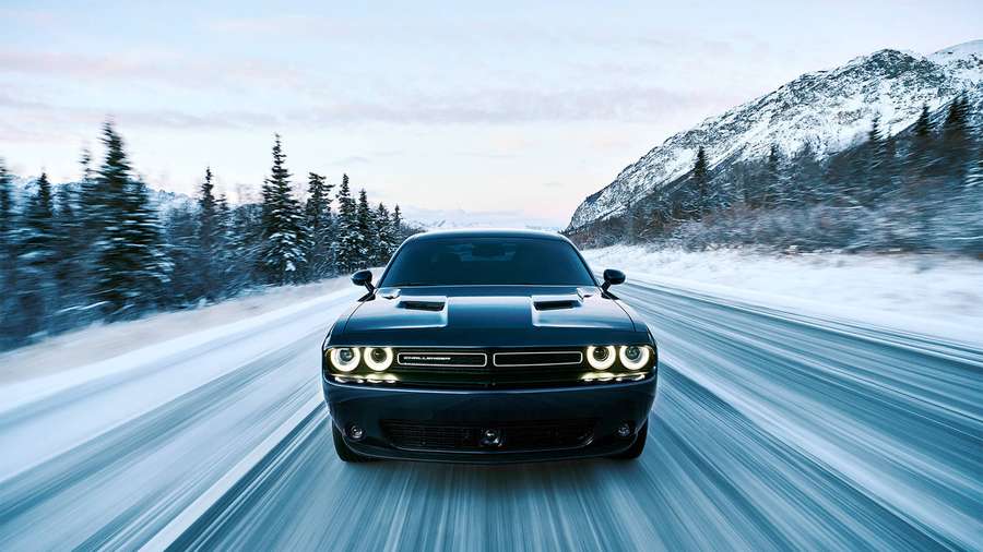 Black Dodge Challenger speeding on snowy mountain road at night — Blue Dodge Challenger Wallpaper