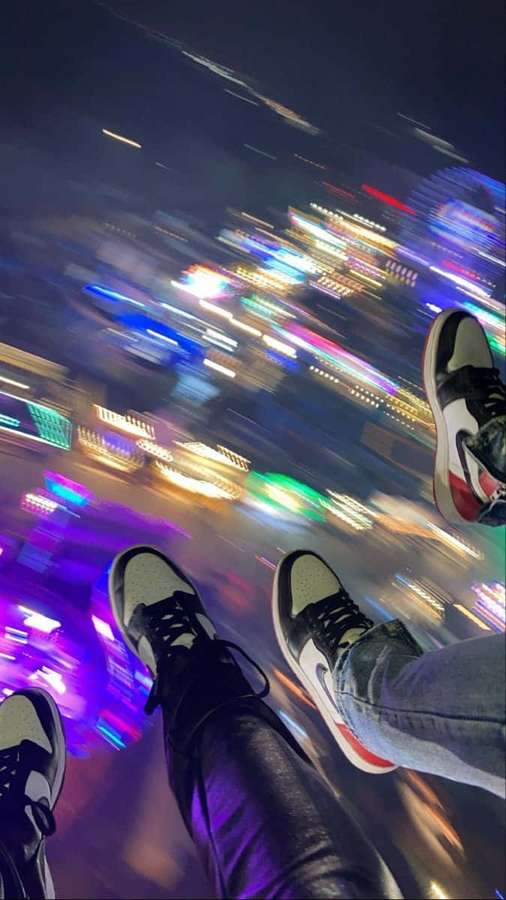 Feet in sneakers dangling over a blurred neon city at night. — Blurry Picture