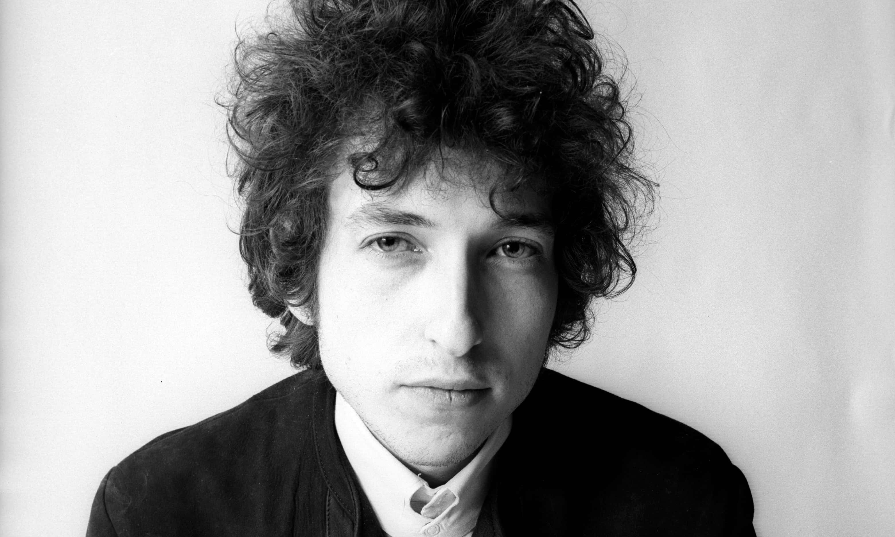 Bob Dylan in a black and white studio portrait with curly hair and a serious expression. — Bob dylan Wallpaper