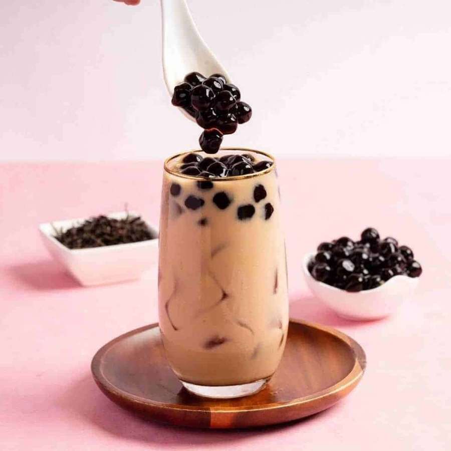 Cremiger Bubble Tea mit schwarzen Perlen, die mit einem Löffel hinzugefügt werden. — Boba Tee Bild Bilder