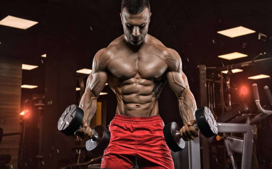 Sportlicher Mann hebt Gewichte im Fitnessstudio mit konzentriertem Ausdruck. — Bodybuilder HD Wallpaper