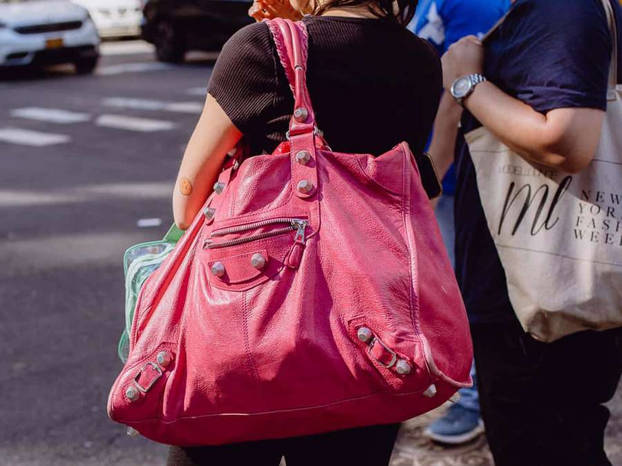Pessoa carregando uma bolsa de couro rosa em uma rua ensolarada da cidade. — Bolsa Papéis de Parede