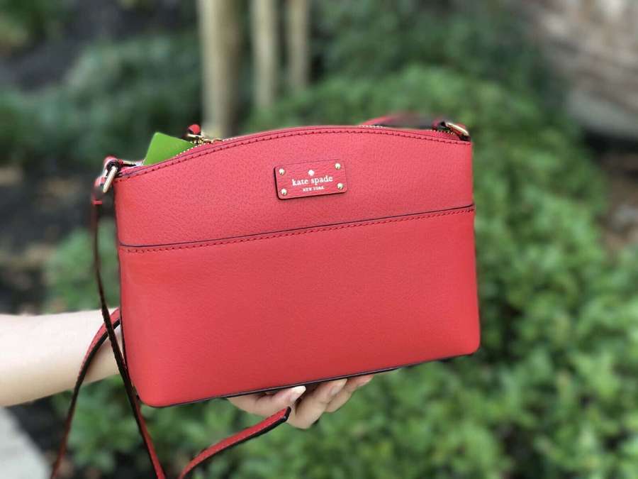 Una persona sostiene un bolso kate spade rojo al aire libre. — Bolso rojo Fondos de pantalla