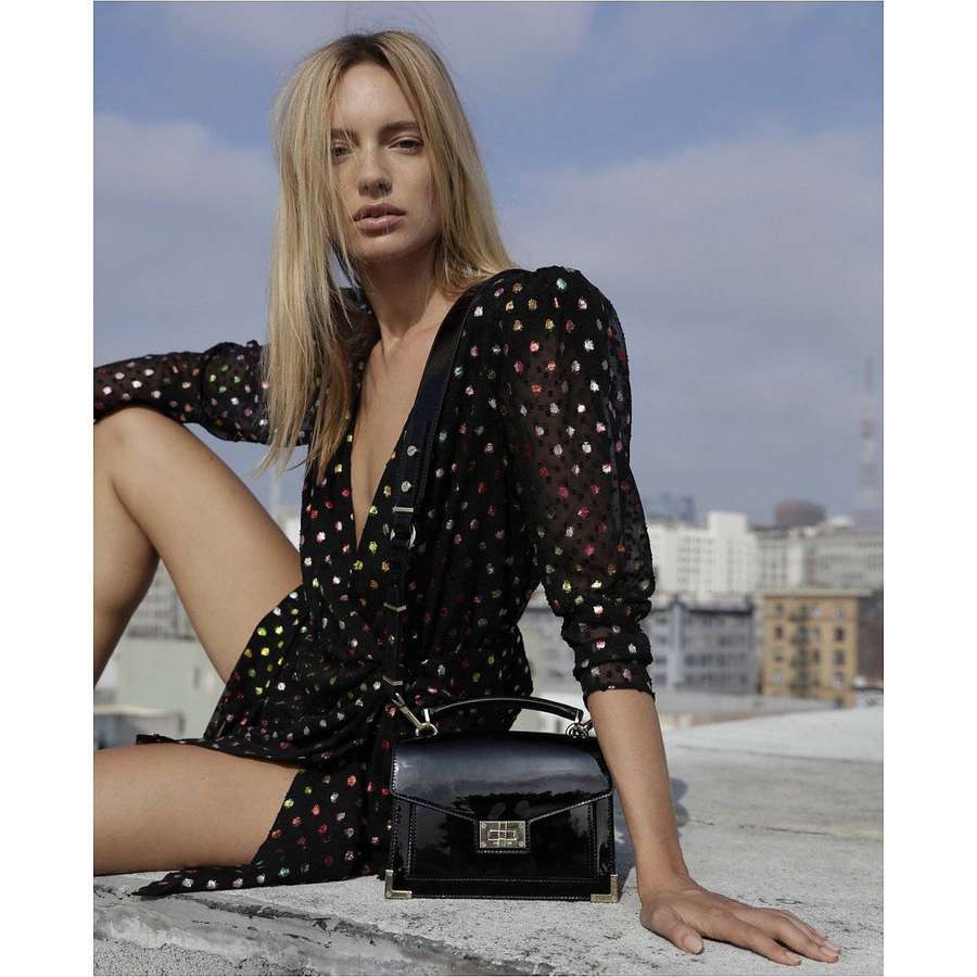 Mujer rubia en vestido floral sosteniendo bolso negro en azotea urbana. — Bolso Fondos de pantalla