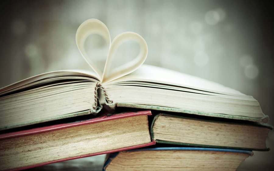 Open book with heart-shaped pages on top of stacked vintage books. — Book Picture