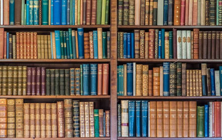 Rows of vintage books on wooden shelves in a library — Bookshelf Wallpaper