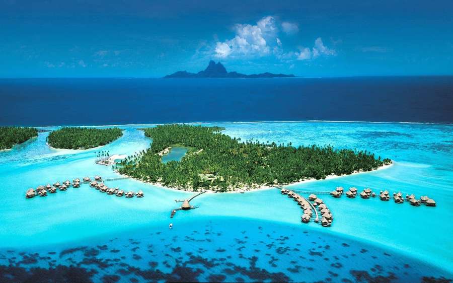 Luxury overwater bungalows on a tropical island with turquoise lagoon and volcanic peaks in distance. — Bora Bora Wallpaper