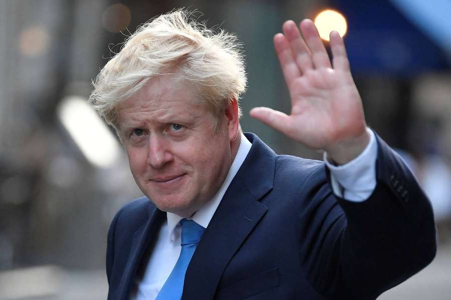 Man in suit and blue tie waving at camera outdoors — Boris Johnson Background