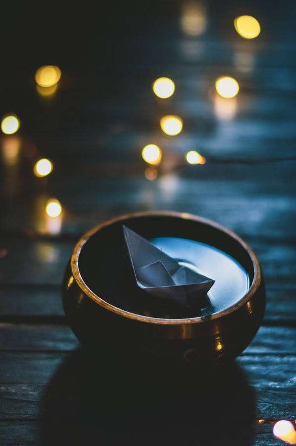 Paper boat in wooden bowl with string lights glowing softly in background. — Bowl Background